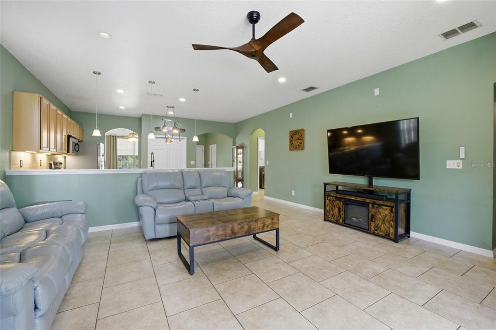 A living room with light gray leather furniture, a wooden coffee table, and green walls — 35937 DAWN DRIVE, LEESBURG, FL