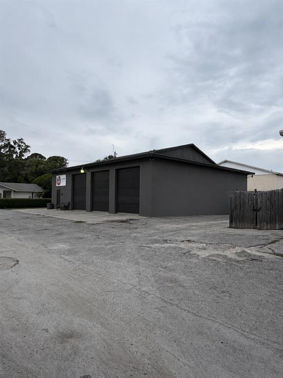 A gray commercial building with three roll-up garage doors sits on a paved lot — 7805 CLARK MOODY BOULEVARD, PORT RICHEY, FL