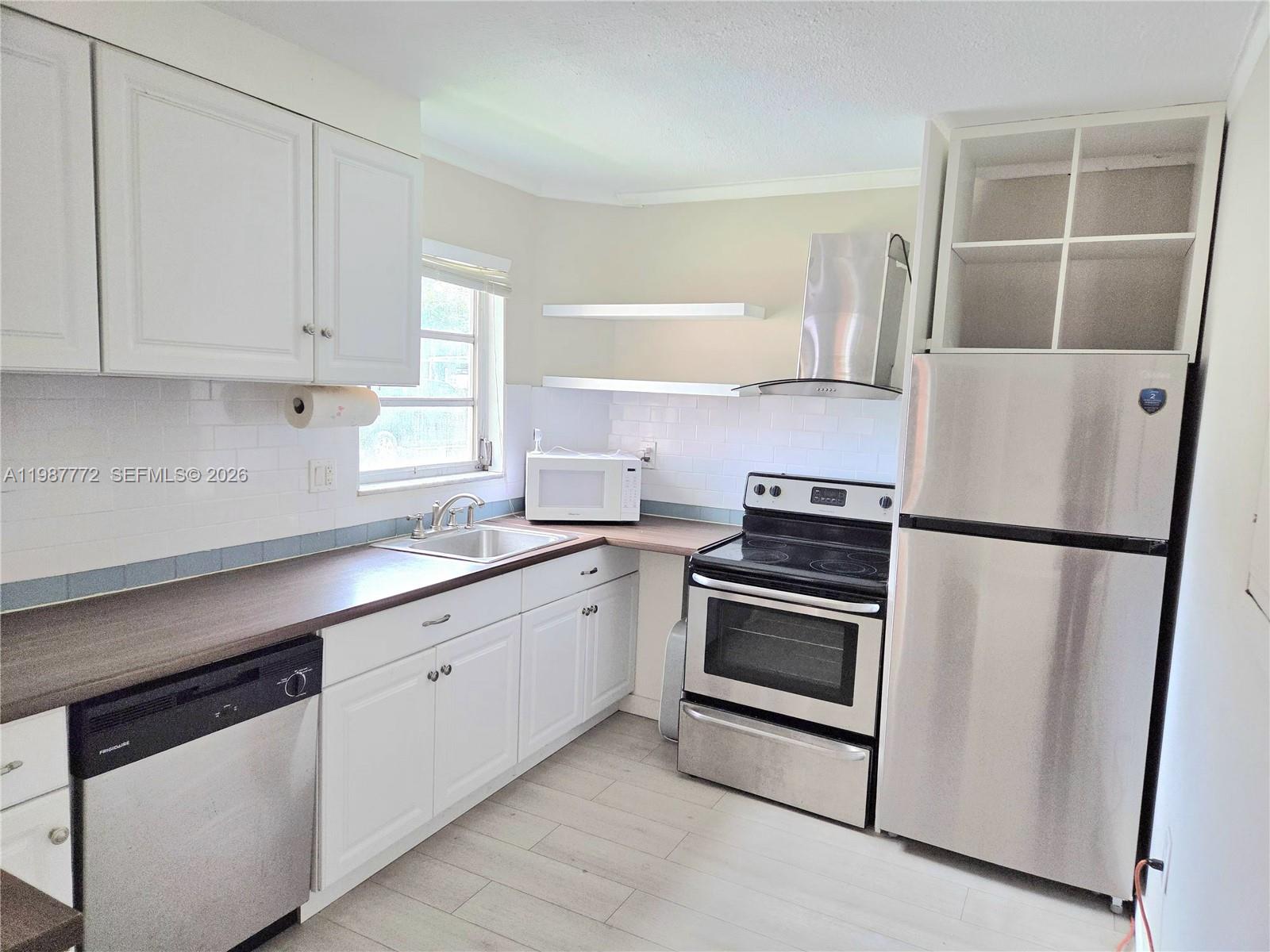 A kitchen features white cabinets, stainless steel appliances, a dark countertop, and light tile flooring — 1700 NE 191st St # 100, Miami FL 33179, MIAMI, FL
