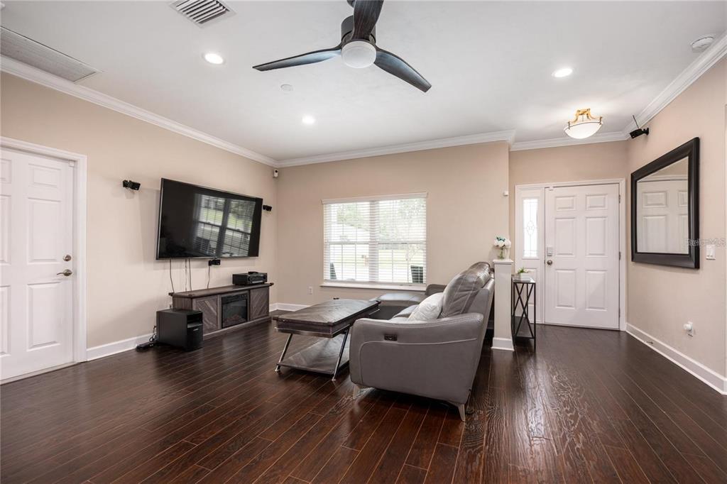 A living room with dark wood floors, a gray sofa, a television, and a ceiling fan — 5504 NW 34TH STREET, GAINESVILLE, FL