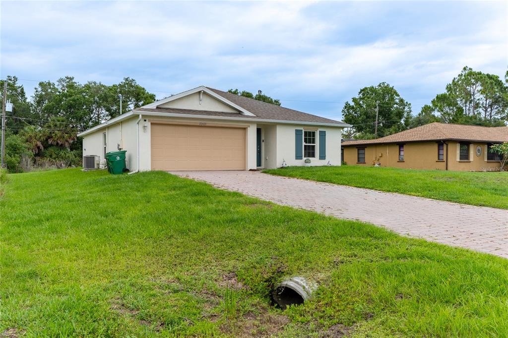 A single-story house with a beige exterior, a two-car garage, and a paved driveway — 22420 SACRAMENTO AVENUE, PORT CHARLOTTE, FL