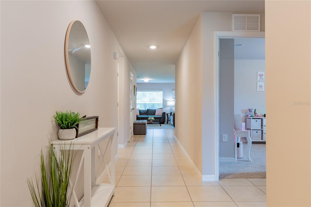 A tiled hallway leads from an entryway with a console table toward a living area — 22420 SACRAMENTO AVENUE, PORT CHARLOTTE, FL