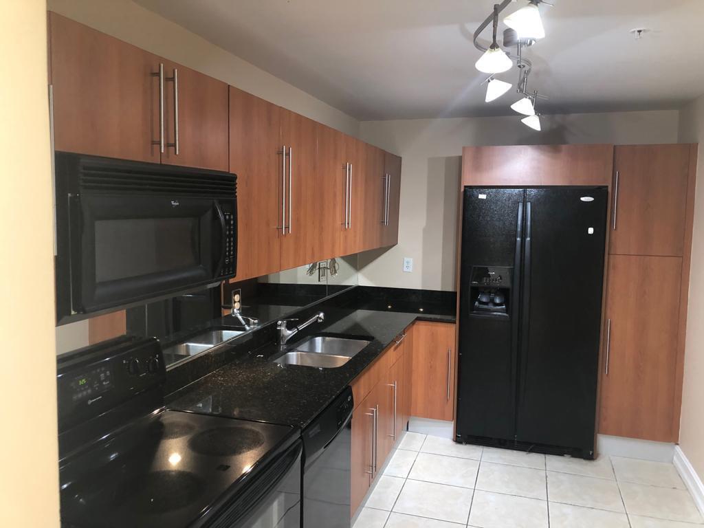 A kitchen with wood-toned cabinets, black appliances, a black countertop, and a mirrored backsplash — 3000 S Ocean Drive # 322, Hollywood FL 33019, HOLLYWOOD, FL