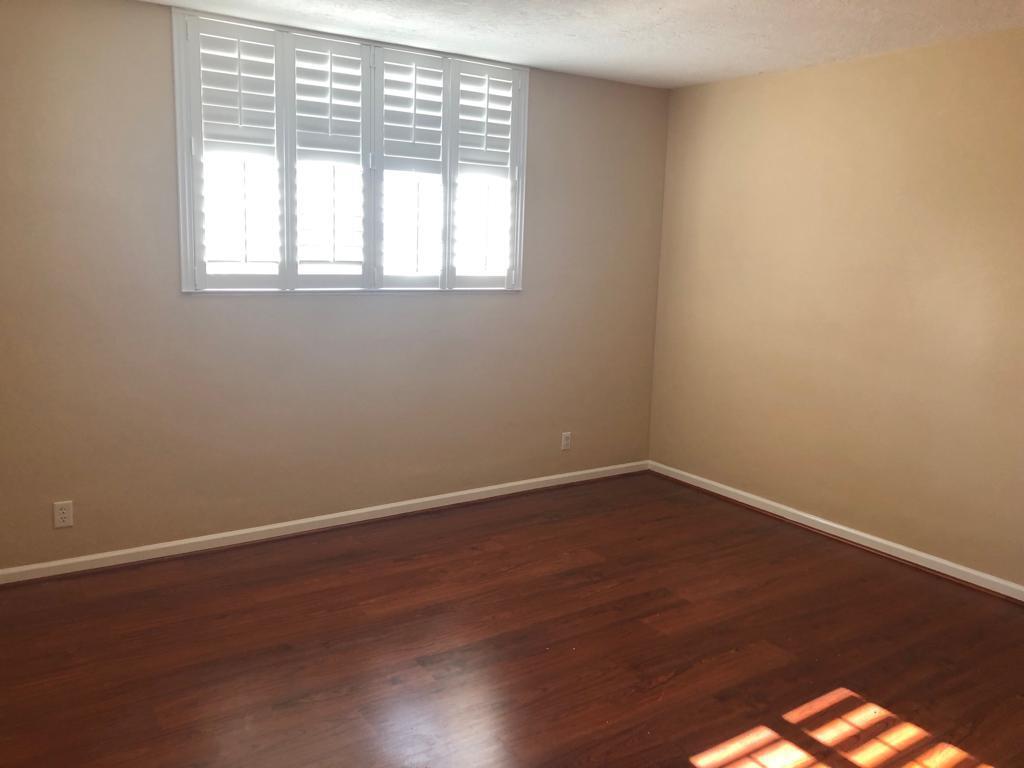 An empty bedroom with hardwood floors, beige walls, and white plantation shutters on the window — 3000 S Ocean Drive # 322, Hollywood FL 33019, HOLLYWOOD, FL