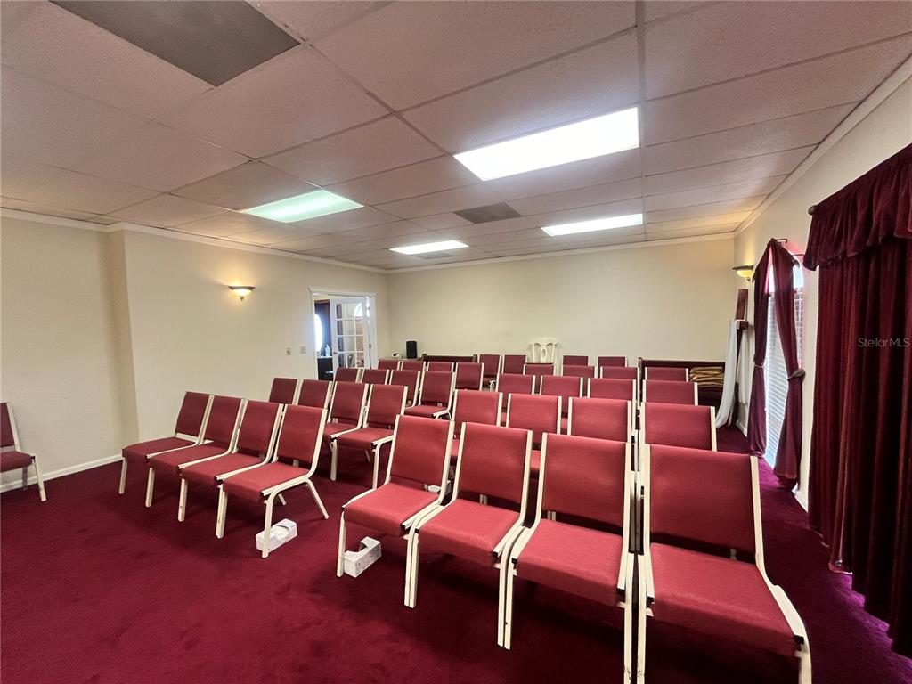 A large room with red carpeting, a drop ceiling, and a television on a stand — 1165 1ST STREET S UNIT 1165, WINTER HAVEN, FL