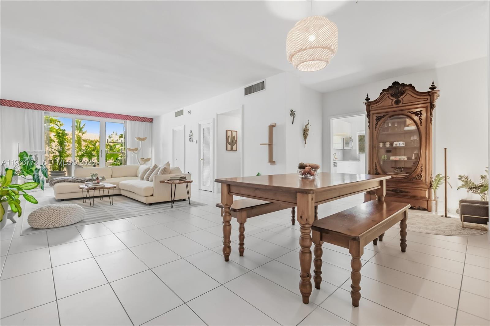 A bright, open-concept living and dining area features white tile floors and wooden furniture — 5001 Collins Ave # 1K, Miami Beach FL 33140, MIAMI BEACH, FL