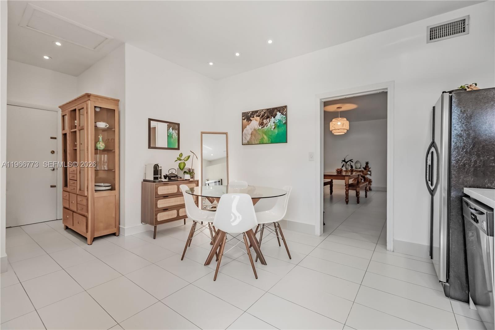 A dining area features a glass table, white chairs, a wooden cabinet, and tile flooring — 5001 Collins Ave # 1K, Miami Beach FL 33140, MIAMI BEACH, FL