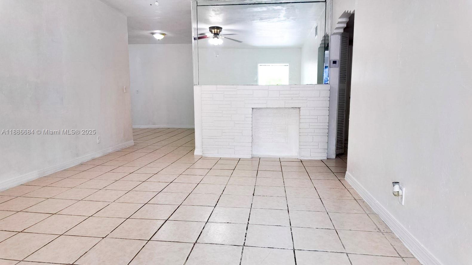 An interior room features light-colored tile flooring, white walls, and a white brick fireplace — 2367 NW 82nd St, Miami FL 33147, MIAMI, FL
