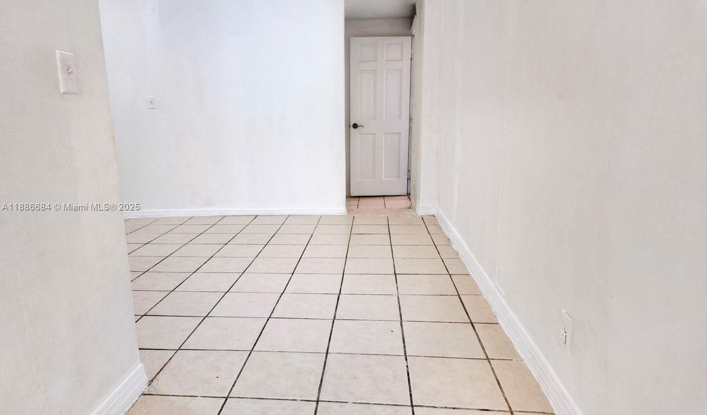 An empty room features white walls, a tiled floor, and a closed white door — 2367 NW 82nd St, Miami FL 33147, MIAMI, FL