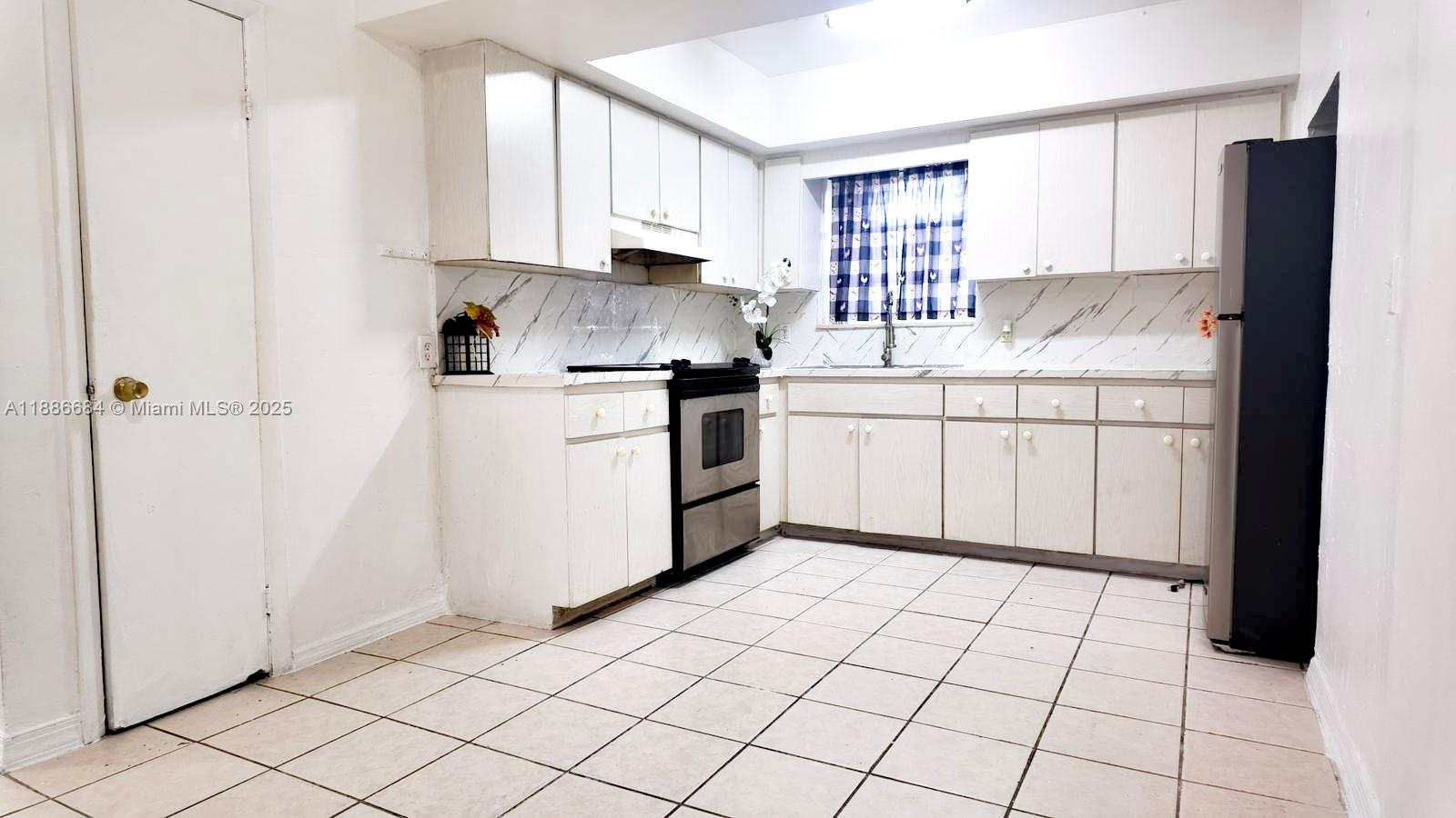 A kitchen features white cabinets, a stainless steel stove, a black refrigerator, and tiled floors — 2367 NW 82nd St, Miami FL 33147, MIAMI, FL
