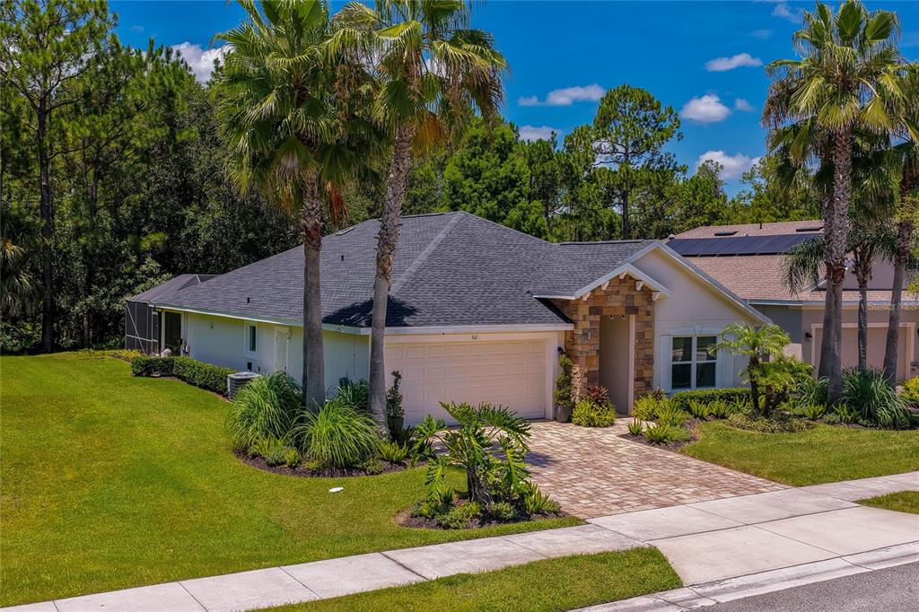 A single-story house with a stone-accented entryway, a two-car garage, and palm trees in front — 312 BIRKDALE DRIVE, DAYTONA BEACH, FL