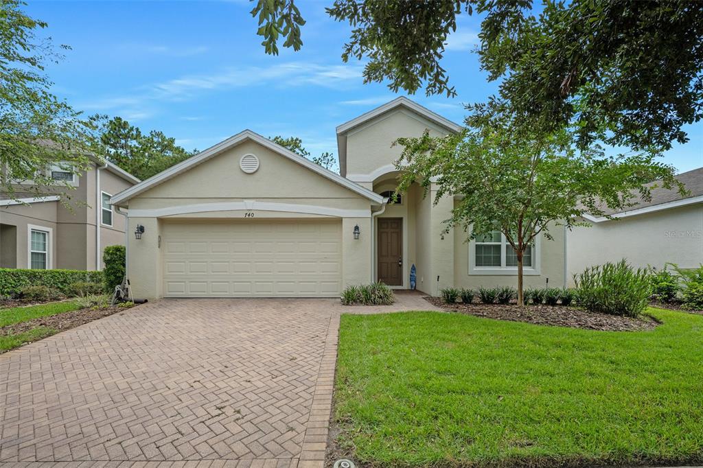 A single-story house with a beige stucco exterior, a two-car garage, and a brick driveway — 740 PREAKNESS CIRCLE, DELAND, FL