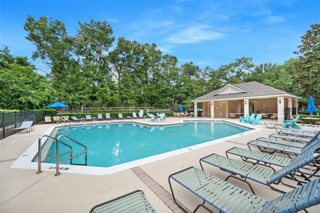 A swimming pool with lounge chairs and a covered patio area surrounded by trees — 740 PREAKNESS CIRCLE, DELAND, FL