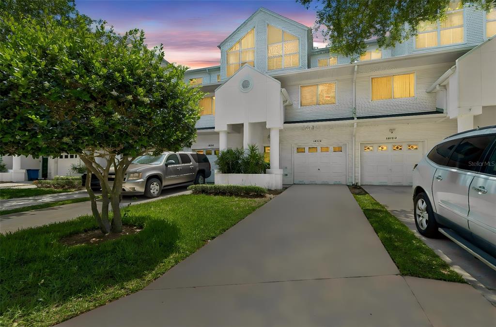 A multi-story townhouse exterior features white siding, a concrete driveway, and two garage doors — 14718 SEMINOLE TRAIL, SEMINOLE, FL