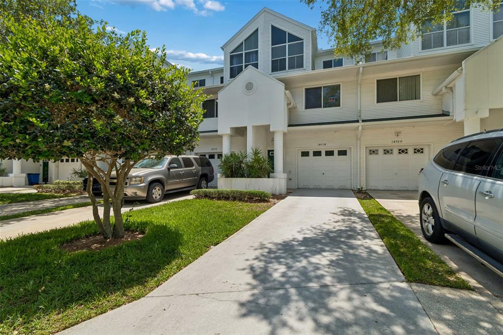 A row of white multi-story townhouses with concrete driveways and parked vehicles in front — 14718 SEMINOLE TRAIL, SEMINOLE, FL