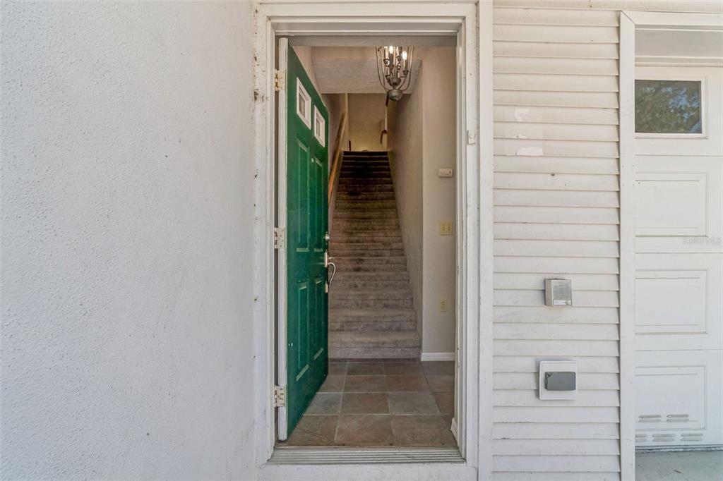 An open green front door reveals an interior entryway with stairs and tile flooring — 14718 SEMINOLE TRAIL, SEMINOLE, FL