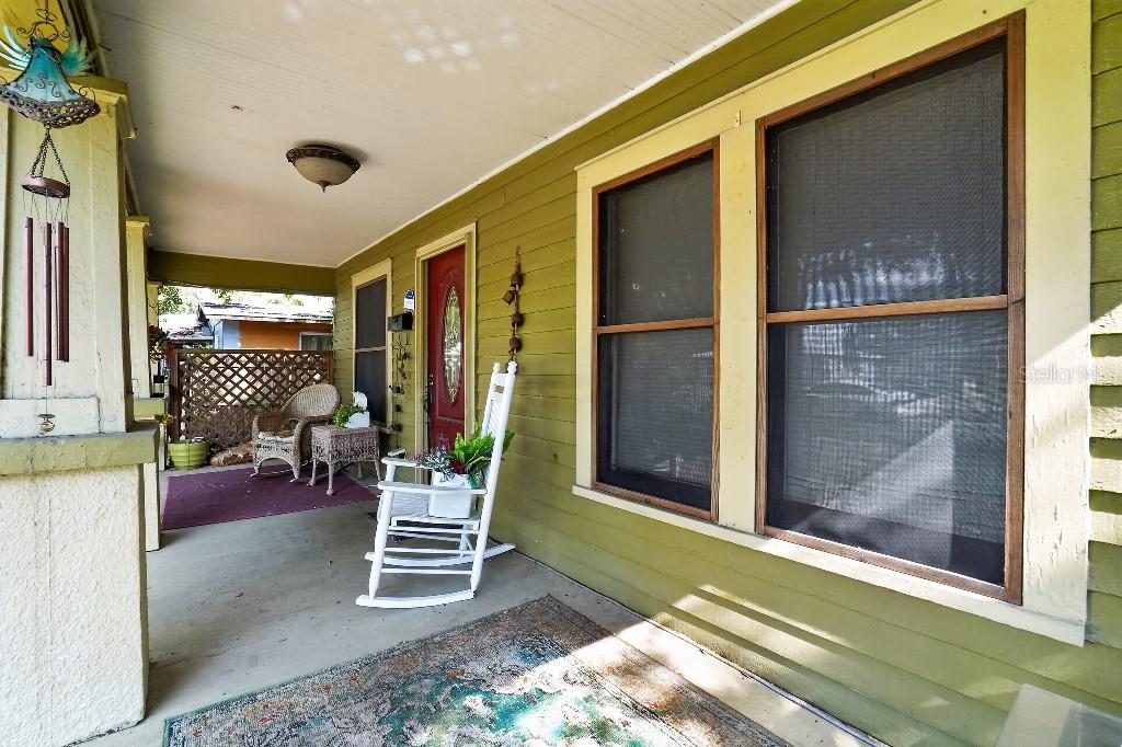 A covered front porch features green siding, a red door, and a white rocking chair — 772 38TH AVENUE S, ST PETERSBURG, FL