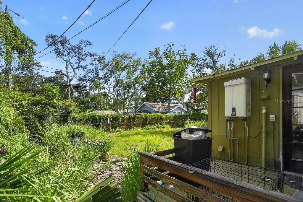A backyard view shows a green exterior wall with a tankless water heater and deck — 772 38TH AVENUE S, ST PETERSBURG, FL