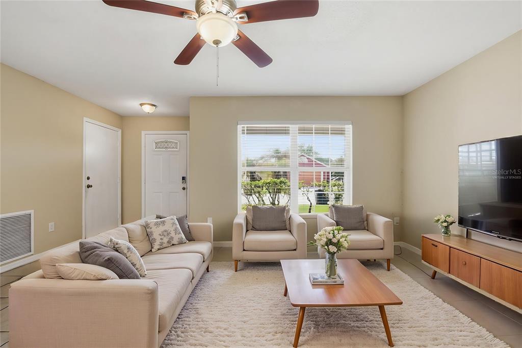 A living room features a beige sofa, two armchairs, a coffee table, and a television — 617 GREYS FERRY ROAD, ORLANDO, FL