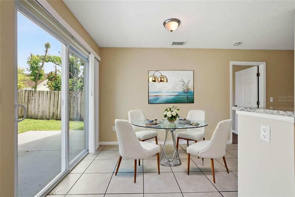 A dining area features a glass-topped table, four white chairs, tile flooring, and sliding doors — 617 GREYS FERRY ROAD, ORLANDO, FL