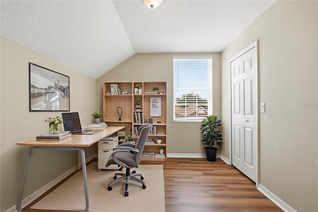 A home office with a wooden desk, bookshelf, gray chair, and wood-look flooring — 617 GREYS FERRY ROAD, ORLANDO, FL