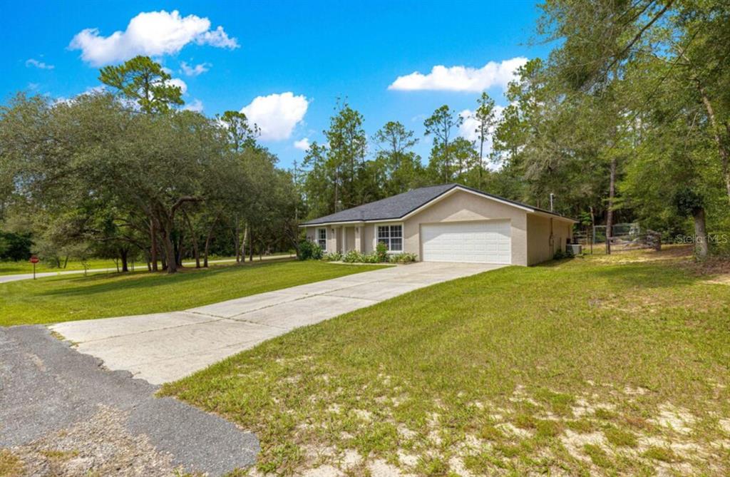 A single-story house with a two-car garage and a concrete driveway sits on a grassy lot — 1423 W HAWK LANE, CITRUS SPRINGS, FL