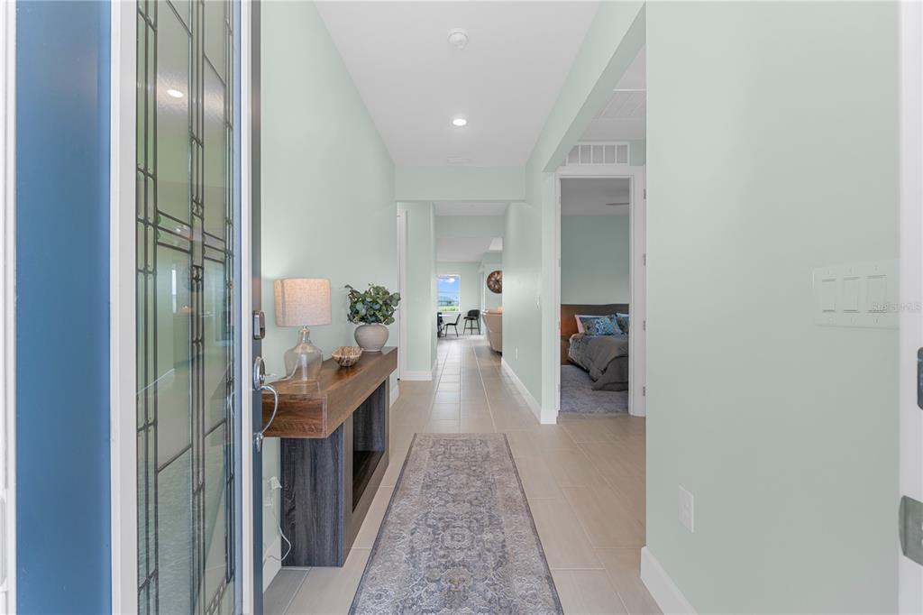 A bright entryway features light green walls, tile flooring, a console table, and a runner rug — 44363 KELLY DRIVE, PUNTA GORDA, FL
