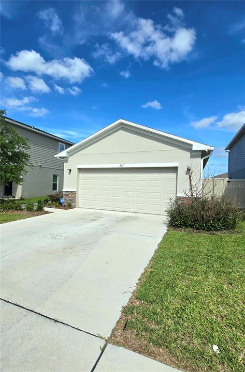 A beige single-story house exterior features a two-car garage and a concrete driveway — 357 WAYLAND DRIVE, HAINES CITY, FL