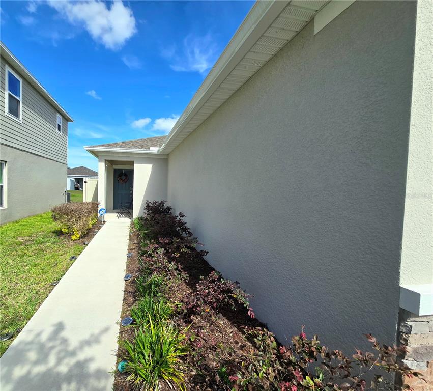 A concrete walkway leads to the front entrance of a house with stucco siding — 357 WAYLAND DRIVE, HAINES CITY, FL