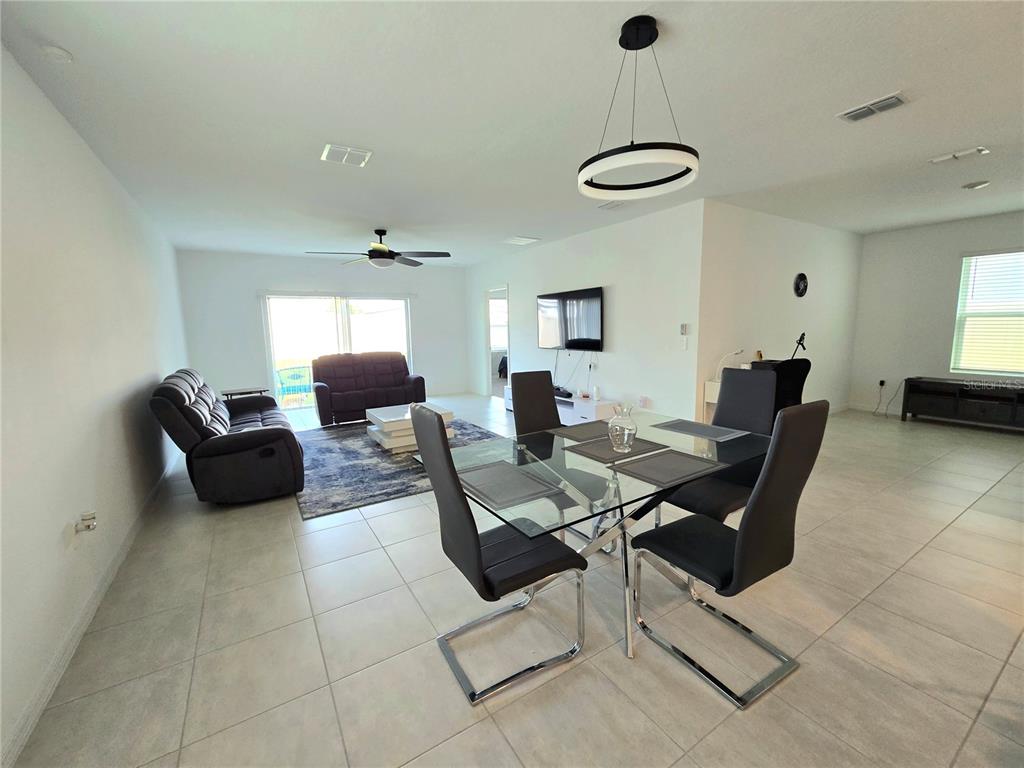 An open-concept living and dining area features tile flooring, a glass table, and dark furniture — 357 WAYLAND DRIVE, HAINES CITY, FL