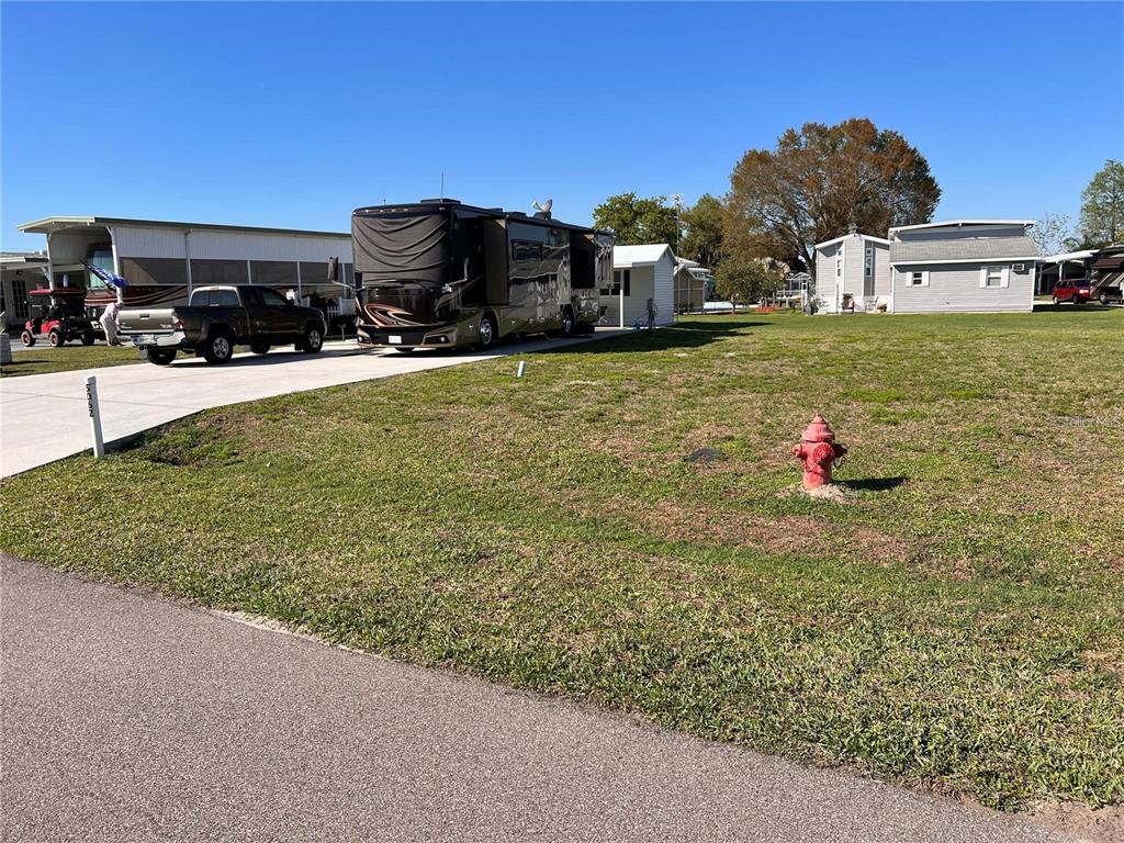 A large motorhome is parked on a concrete driveway next to a grassy lawn — 5062 SOUTHSHORE DRIVE, POLK CITY, FL