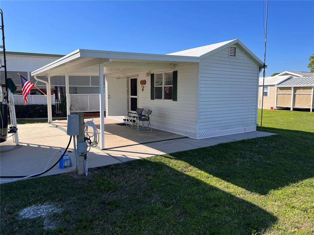 A white mobile home features a covered carport, a concrete patio, and a small lawn — 5062 SOUTHSHORE DRIVE, POLK CITY, FL