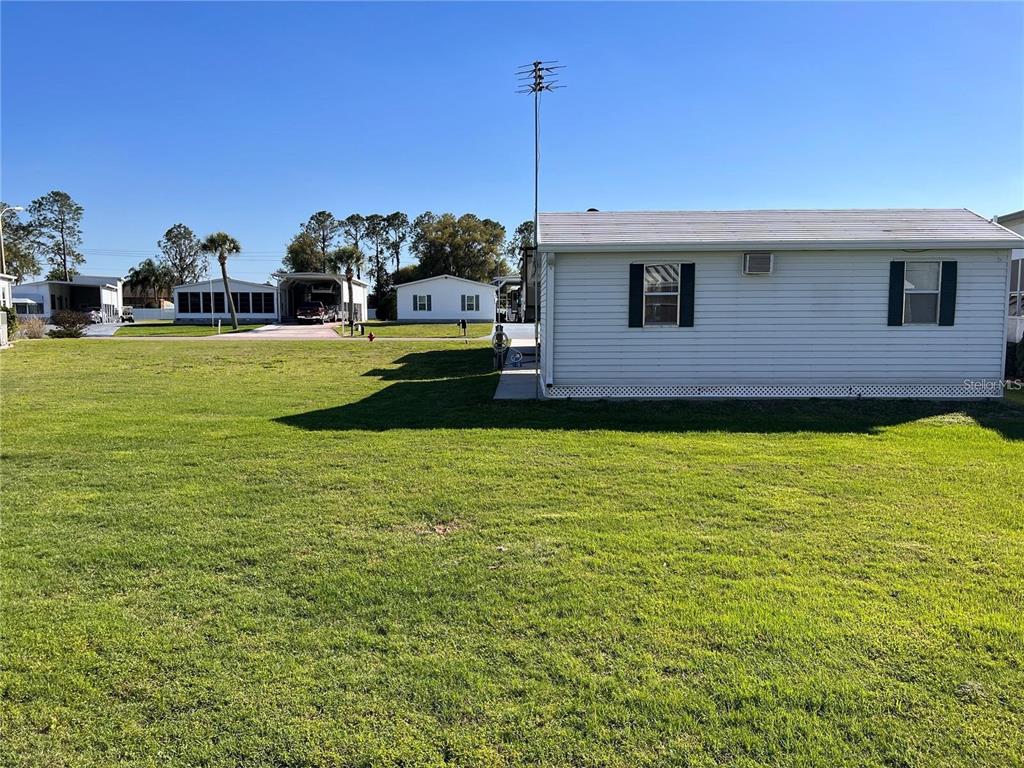 A side view of a white mobile home with a large grassy yard — 5062 SOUTHSHORE DRIVE, POLK CITY, FL