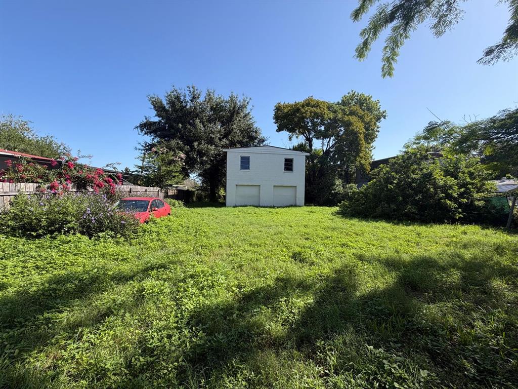A detached two-car garage sits at the back of a large, overgrown grassy lot — 375 TRAILER LANE, KISSIMMEE, FL