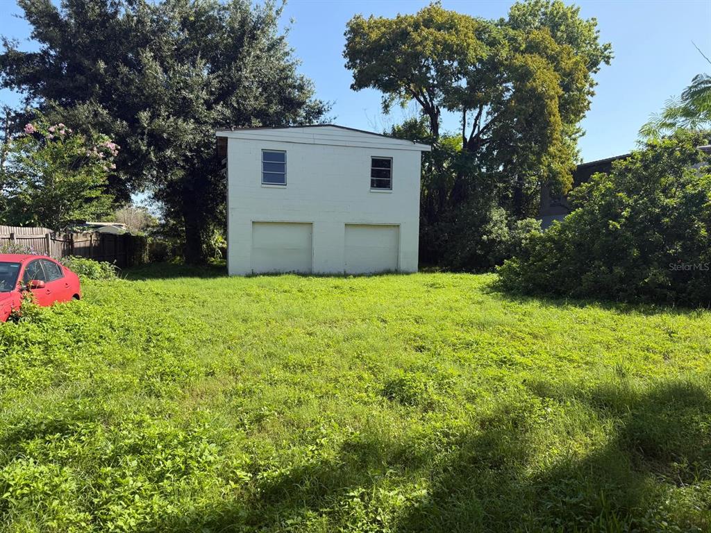 A two-story detached garage sits at the back of a grassy, overgrown lot — 375 TRAILER LANE, KISSIMMEE, FL