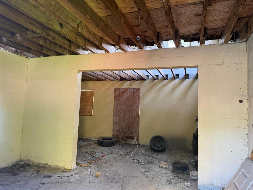 An unfinished room with exposed ceiling joists, concrete block walls, and a dirt floor — 375 TRAILER LANE, KISSIMMEE, FL