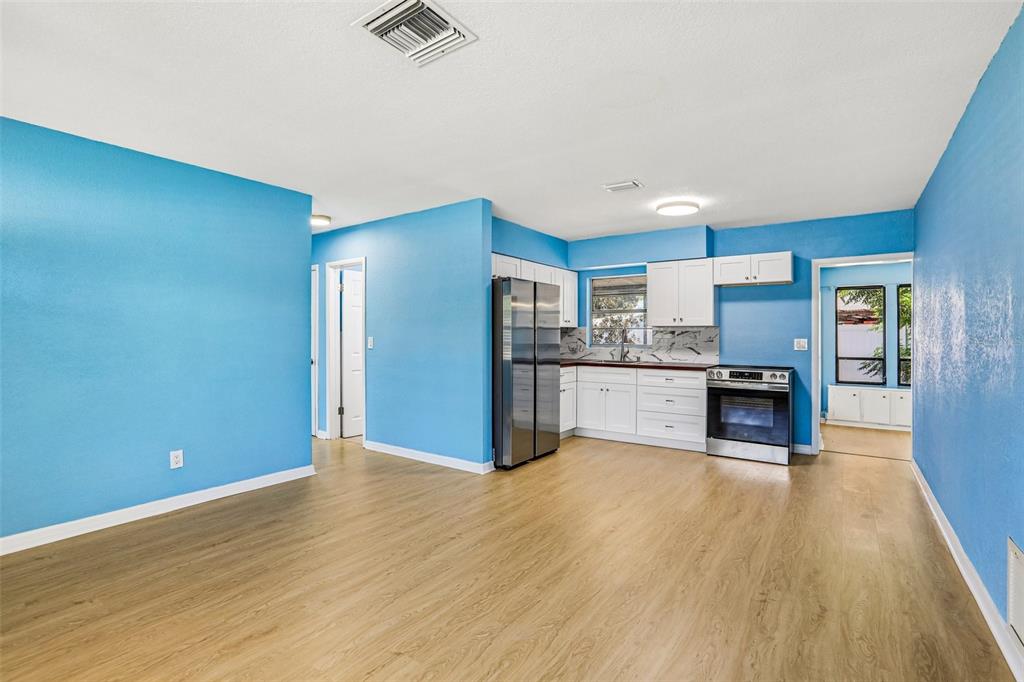 A kitchen with white cabinets and stainless steel appliances opens to a blue-walled living area — 104 E GRAPEFRUIT CIRCLE, CLEARWATER, FL