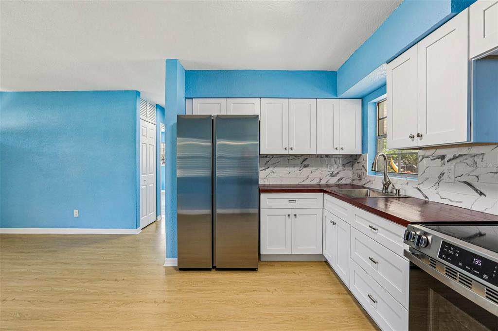 A living room with blue walls, a beige sectional sofa, and an adjacent kitchen area — 104 E GRAPEFRUIT CIRCLE, CLEARWATER, FL