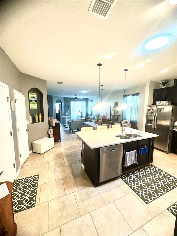 A kitchen with a central island and stainless steel appliances opens into a living area — 16484 CENTIPEDE STREET, CLERMONT, FL