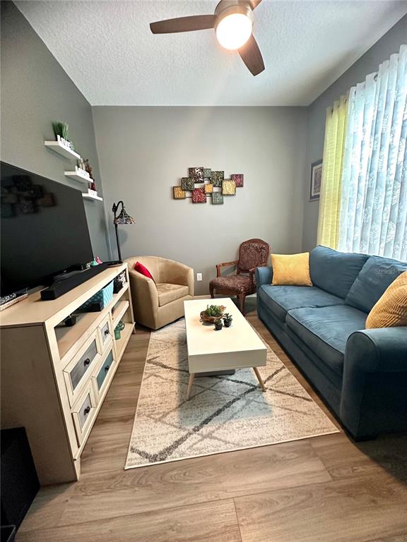 A living room features a blue sofa, a beige armchair, a coffee table, and a television — 16484 CENTIPEDE STREET, CLERMONT, FL