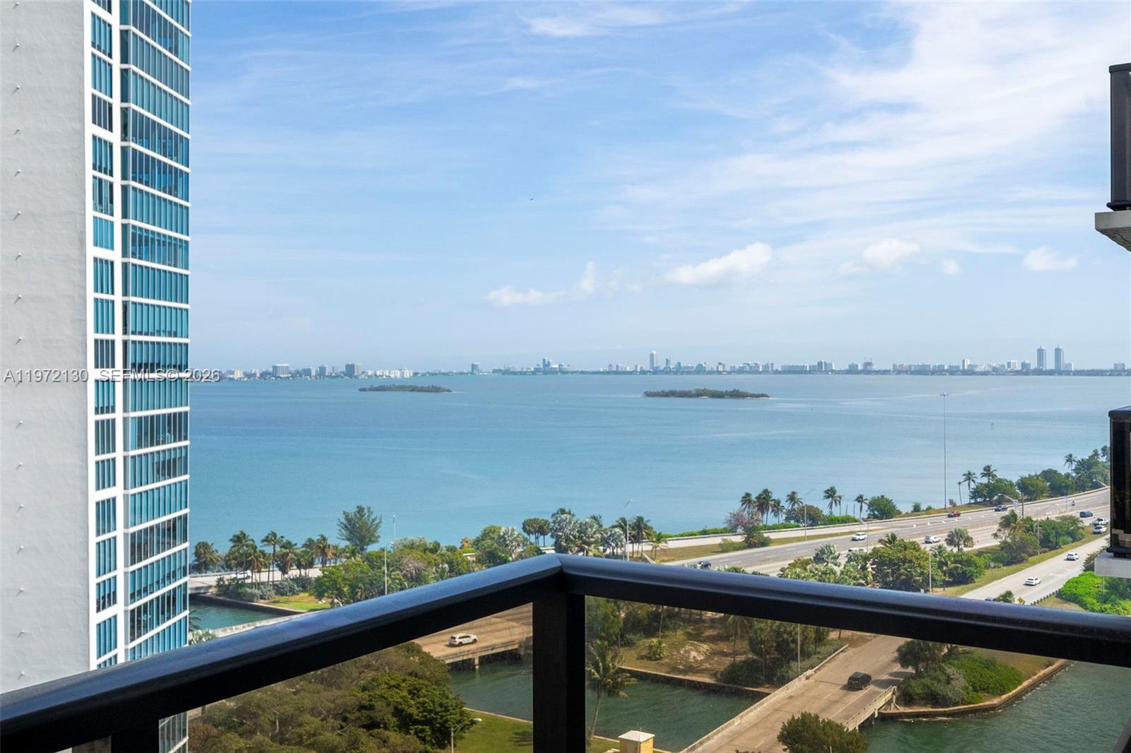 A high-rise balcony overlooks a bay, a highway, and a distant city skyline — 600 NE 36th St # 1815, Miami FL 33137, MIAMI, FL