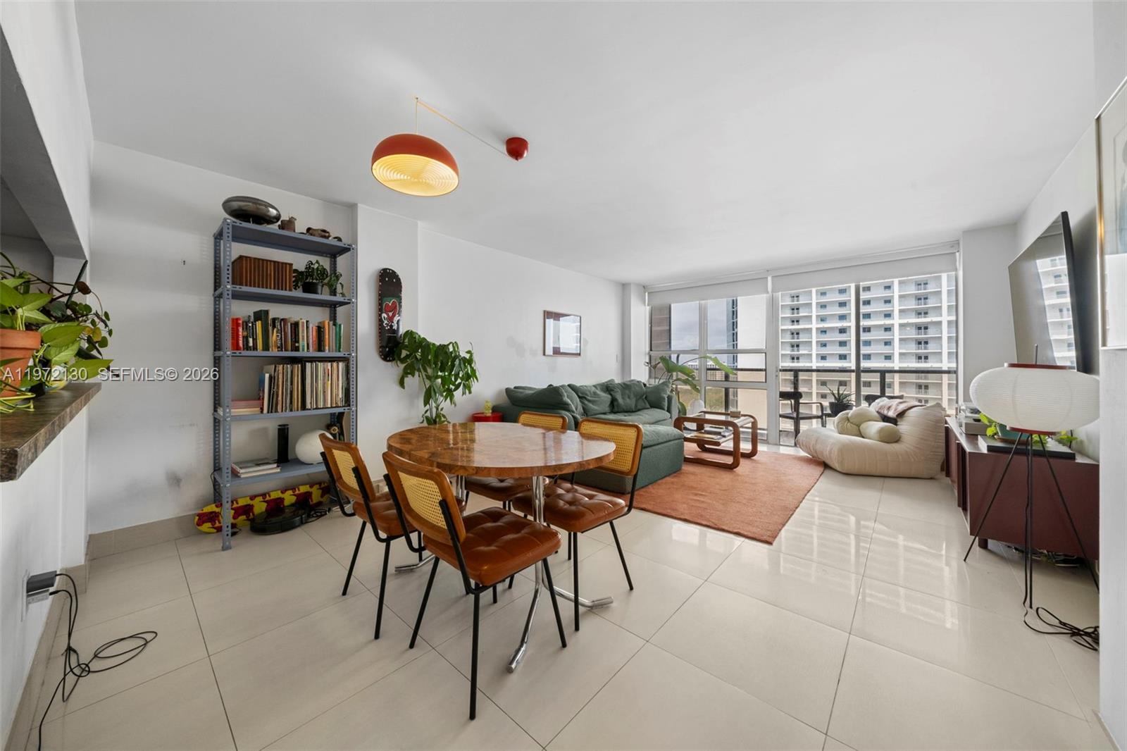 A living and dining room features tile floors, a round wooden table, and a balcony view — 600 NE 36th St # 1815, Miami FL 33137, MIAMI, FL