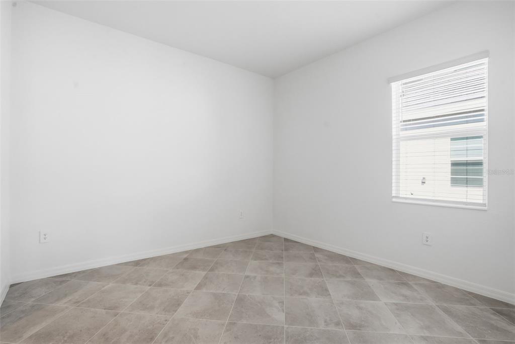 An empty room features white walls, a single window with blinds, and gray tiled flooring — 19715 TROUT TERRACE, LAKEWOOD RANCH, FL