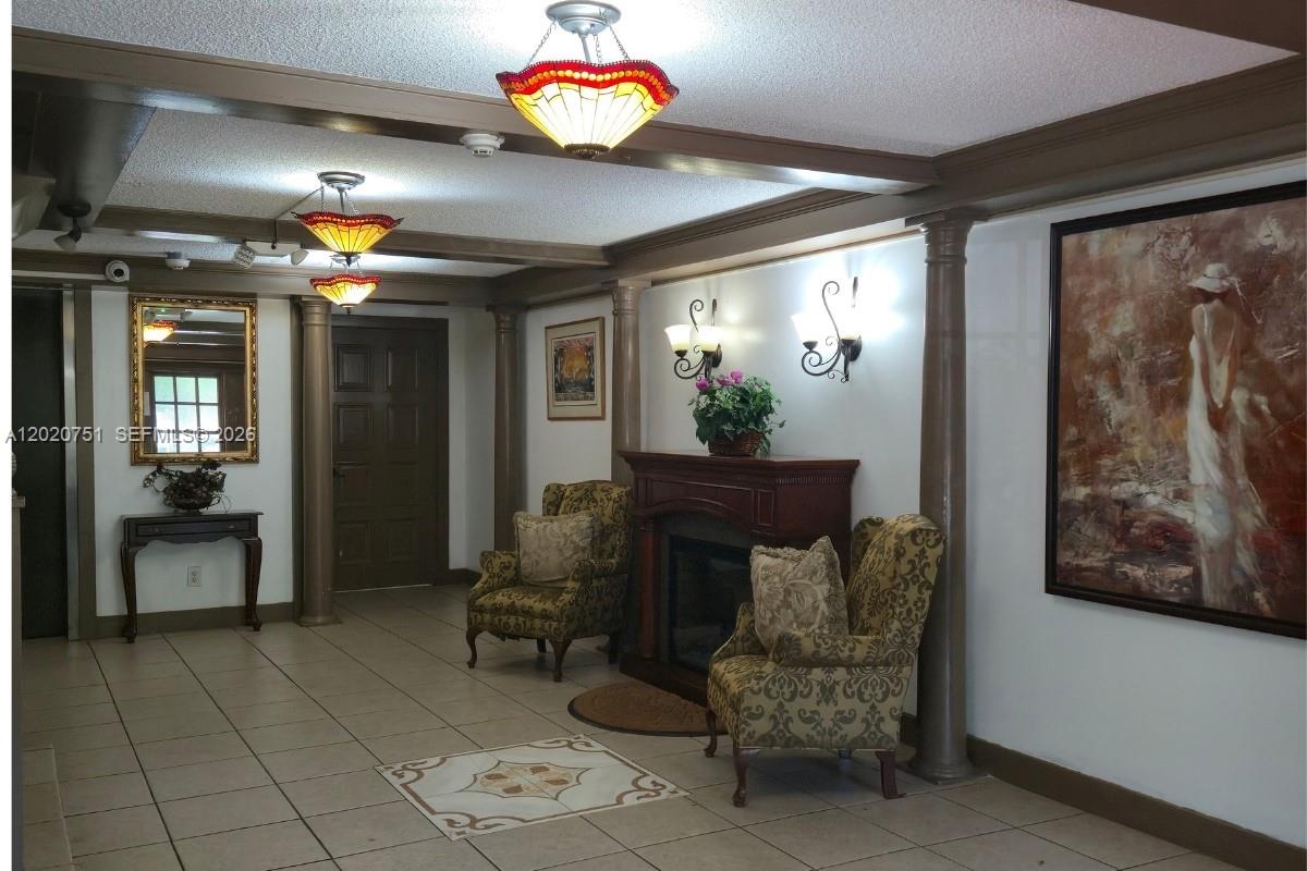 A lobby area features tile flooring, a fireplace, two patterned armchairs, and decorative lighting fixtures — LAUDERHILL, FL