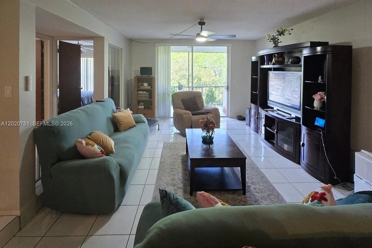 A living room features a teal sofa, a dark wood coffee table, and tile flooring — LAUDERHILL, FL