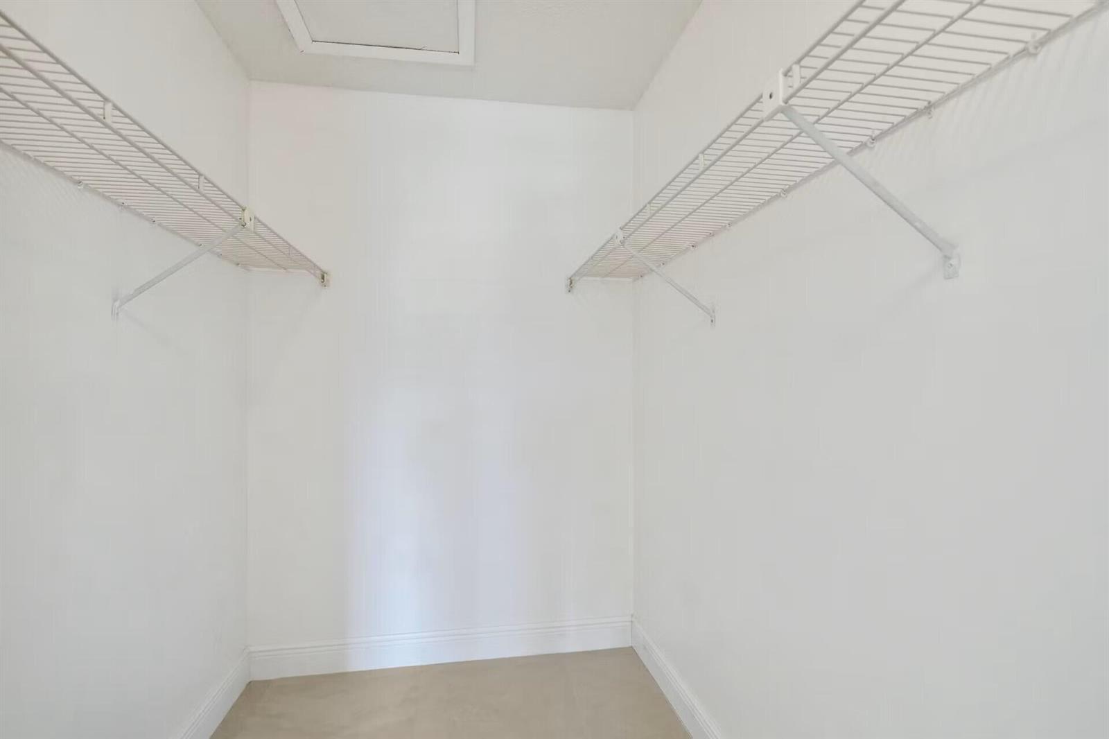 A walk-in closet with white walls, beige flooring, and two white wire shelving units — 802 Sky Pine Way # E2, FL 33415, FL