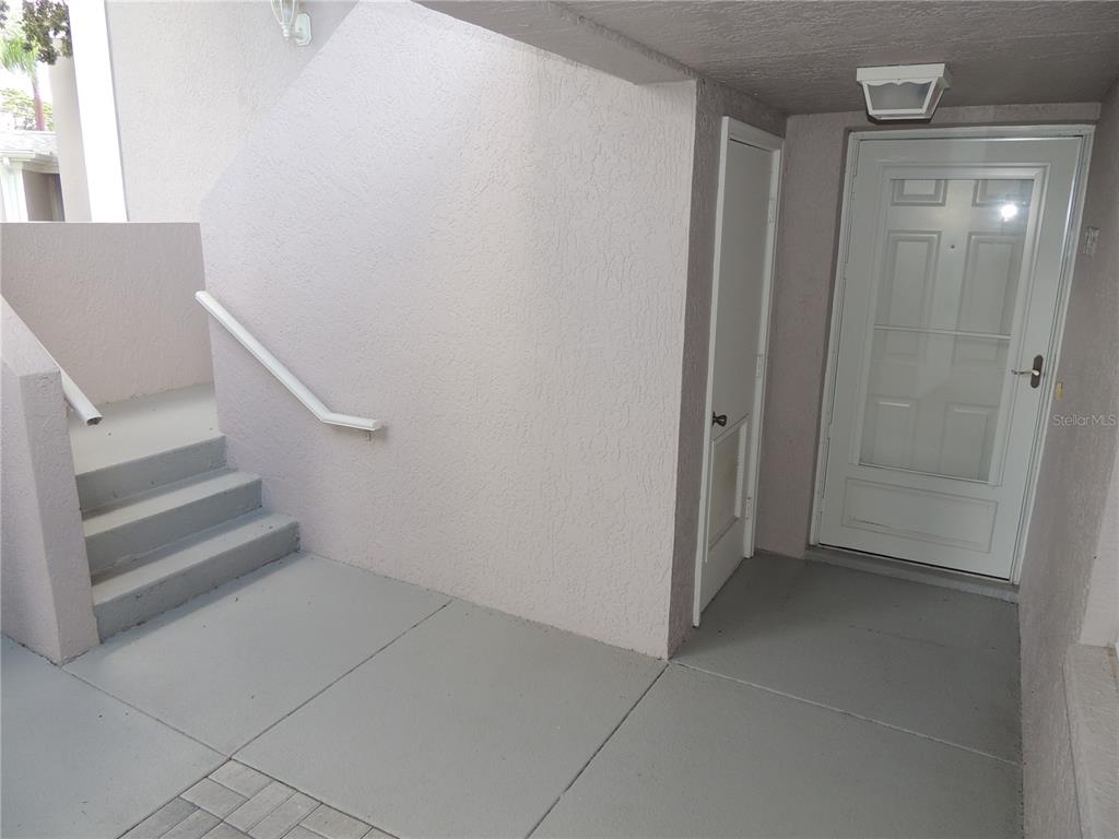 An exterior entryway features a white door, a small storage closet, and concrete stairs — 5667 SHEFFIELD GREENE CIRCLE UNIT 59, SARASOTA, FL