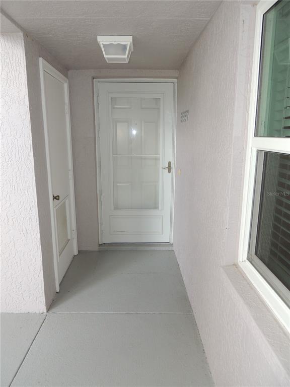 A white front door and a smaller side door are located on a covered porch — 5667 SHEFFIELD GREENE CIRCLE UNIT 59, SARASOTA, FL
