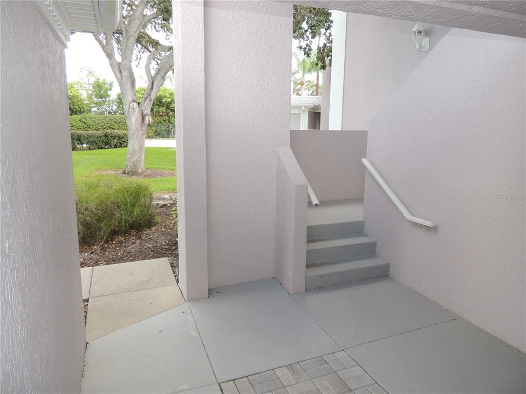 A covered entryway features a concrete floor, a small set of stairs, and exterior walls — 5667 SHEFFIELD GREENE CIRCLE UNIT 59, SARASOTA, FL