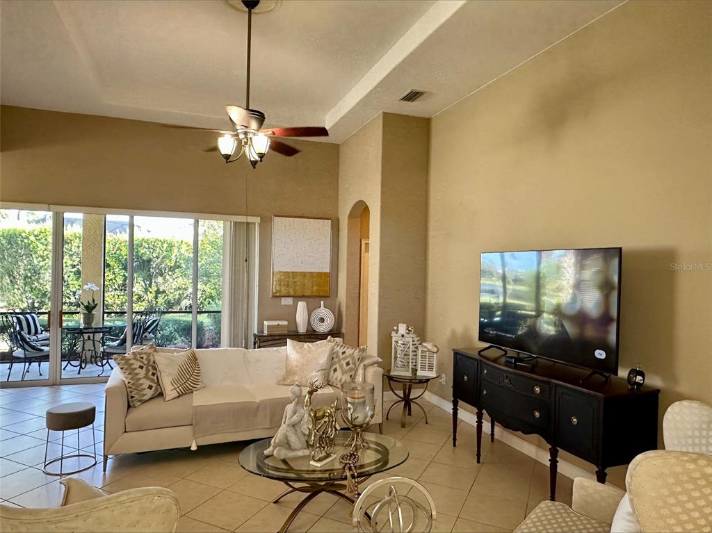 A living room features a beige sofa, glass coffee table, and a television on a console — 137 MEDICI TERRACE, NORTH VENICE, FL